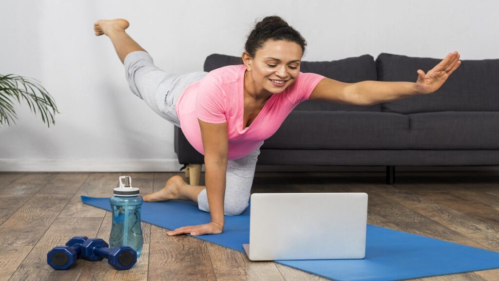  home exercising yoga with laptop